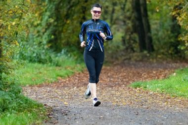 A man jogging on a tree-lined path during autumn in Frankfurt, Germany.
